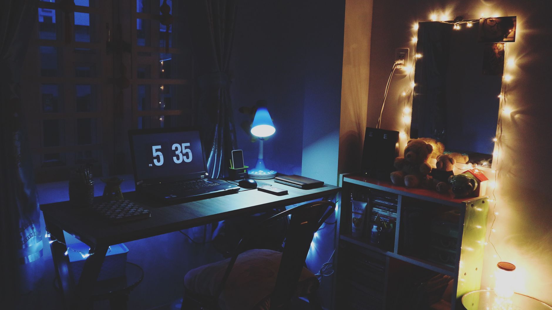 Escritorio nocturno con portátil y luces cálidas, ambiente de trabajo tranquilo desde casa.