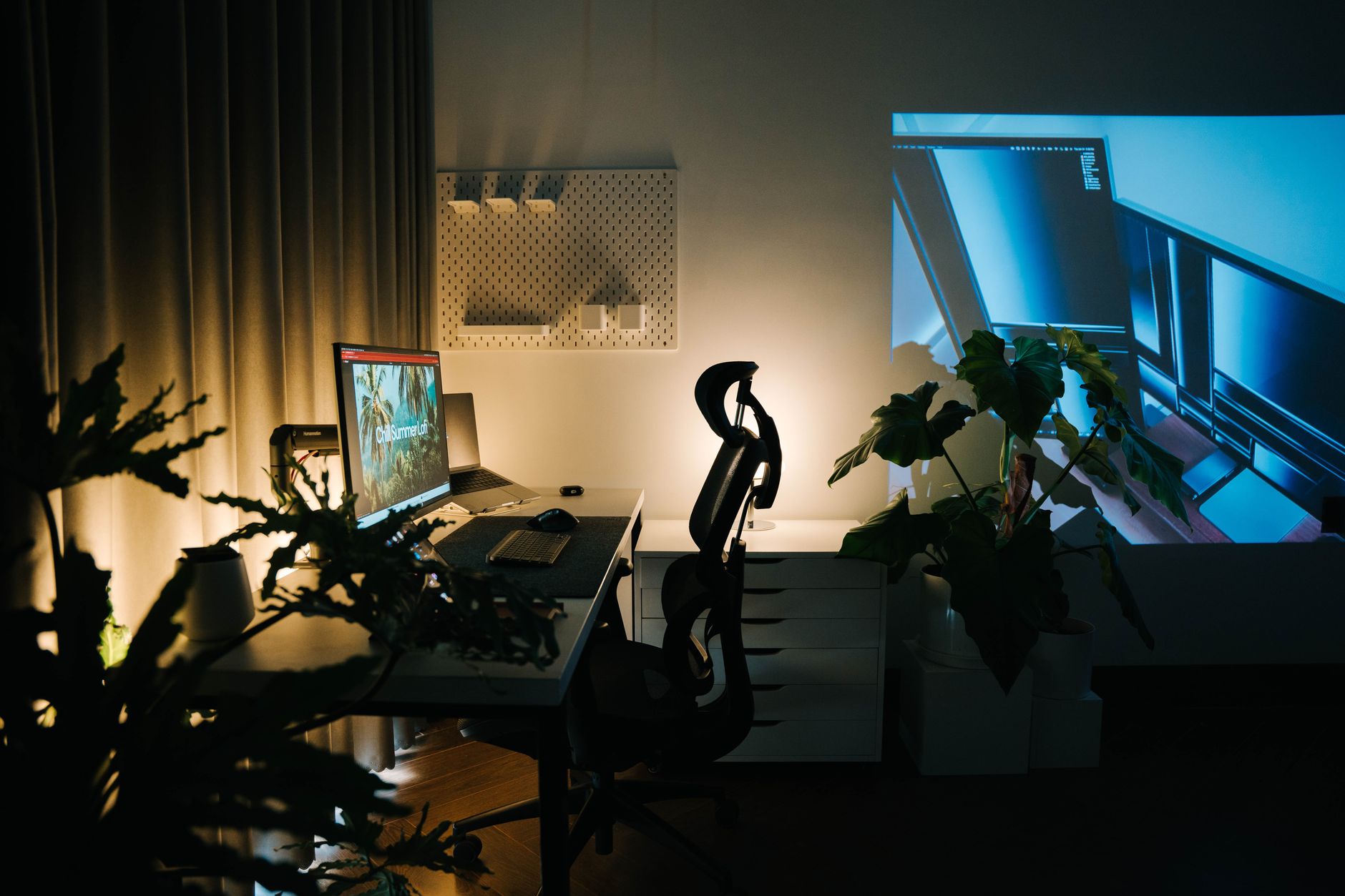 Espacio de trabajo acogedor en casa con plantas, luz ambiental y ordenador.