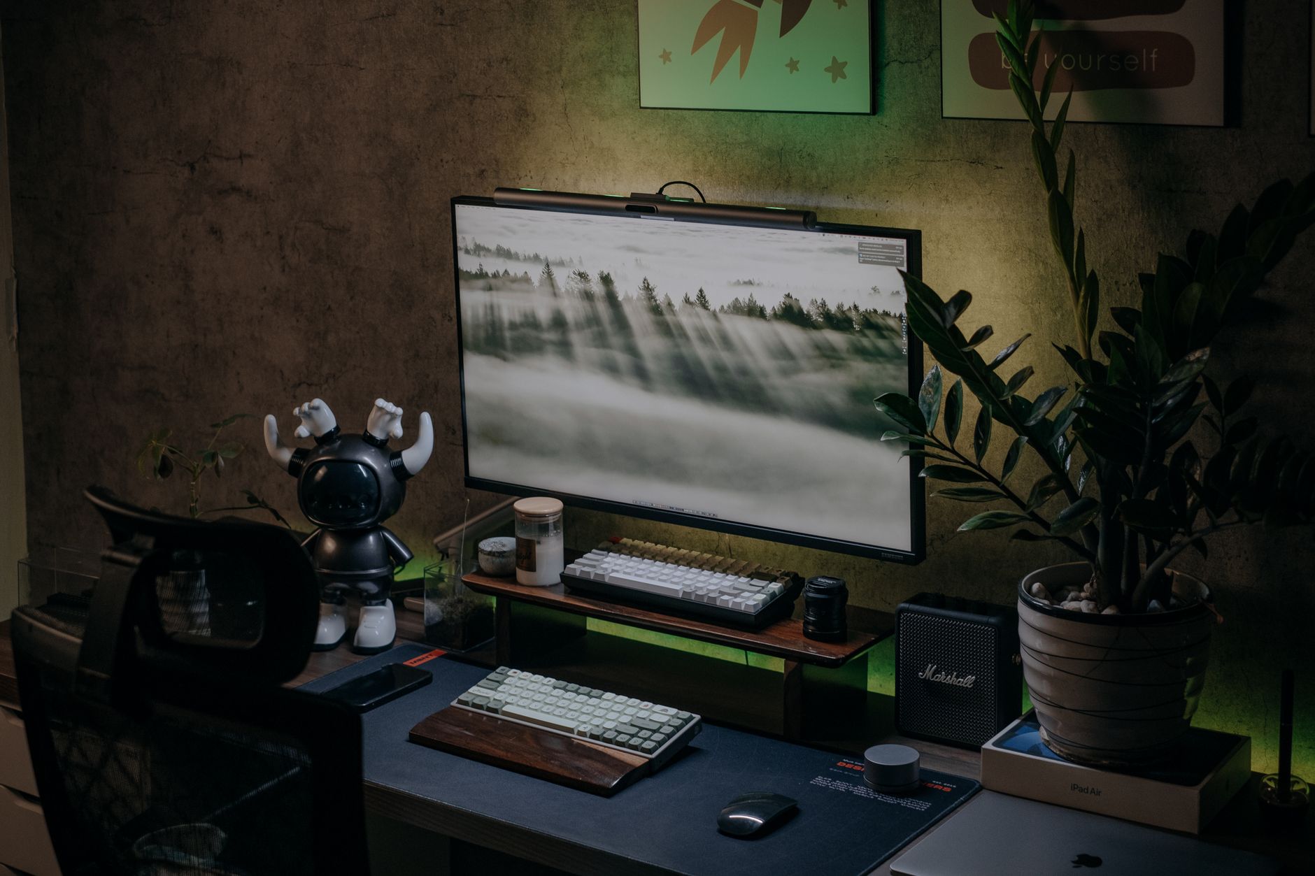 Escritorio con monitor, teclado, plantas y decoración cuidada en un ambiente acogedor.
