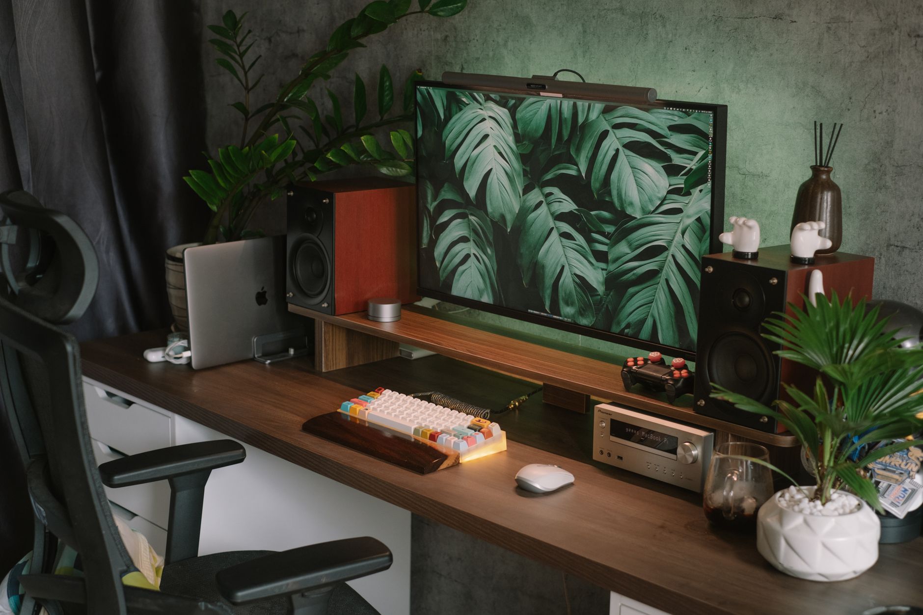 Monitor vintage entre plantas y tecnología moderna en un espacio de trabajo con carácter.